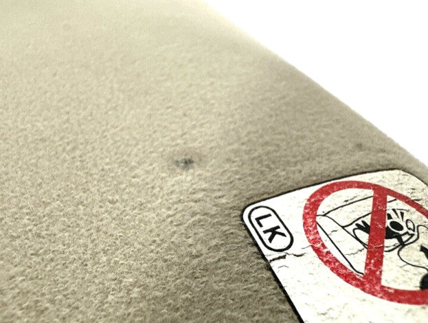 Close-up of a textured surface with a sticker featuring a 'No Littering' symbol.