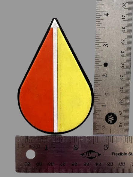 Colorful teardrop-shaped object with a ruler for scale on a white background